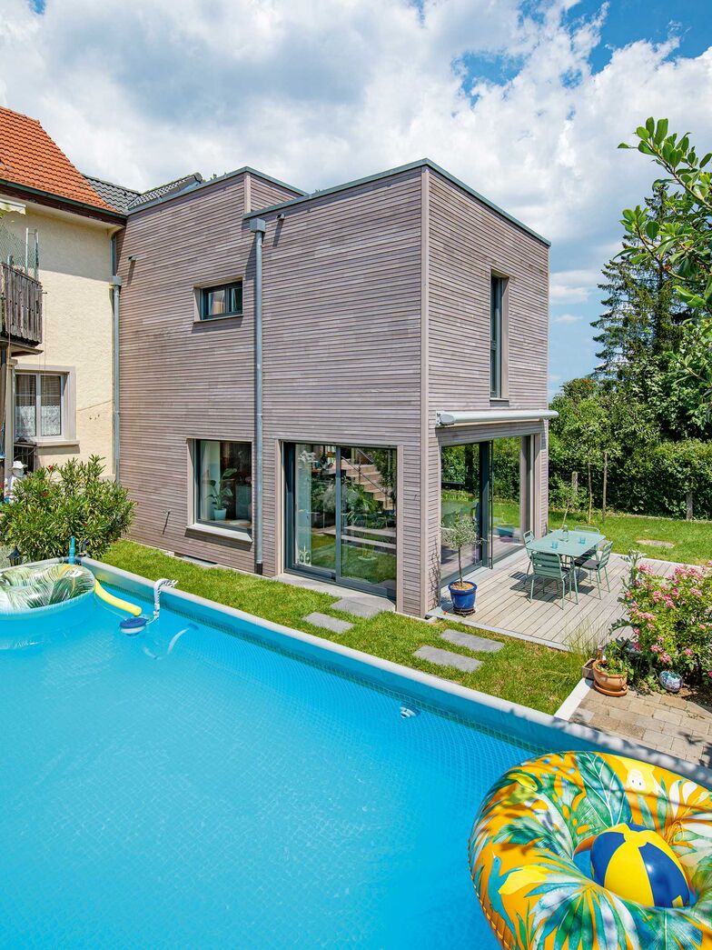 Der Winkel zwischen Alt- und Neubau bildet einen geschützten Bereich und ist ein idealer Platz für den Pool der Gross­familie.