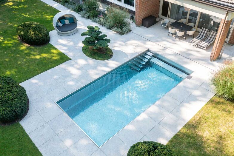 Die klare Geometrie von Pool und Keramikplatten wird durch die sanften, runden Pflanzeninseln aufgelockert.