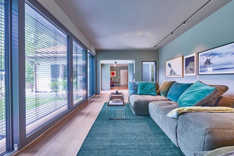 Auch das Wohnzimmer im Anbau mit den Grüntönen des Sofas, der Kissen und der Wandfarbe bilden eine Einheit mit dem Garten. Dessen wilde Schönheit war ausschlaggebend für die Kaufentscheidung des Bauherrn und Architekten.