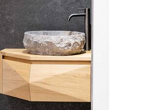 Die Eckbadmöbel aus massivem Eichenholz sind ideal für kleinere Badezimmer und bieten funktionale Eleganz. Sie werden ergänzt durch Flusssteinbecken, die aufgrund ihrer natürlichen Beschaffenheit jedes für sich ein Unikat darstellen. Schreinerei Fehlmann AG.