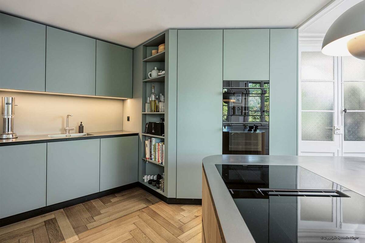 Diese Küche trägt den Namen «Le cœur de l’artichaut». Das «Artischockenherz» ist der essbare Blütenboden der Pflanze und gilt als Delikatesse. Die zarte Farbwahl harmoniert mit dem Fischgerätenparkett und den hellen Wänden des Altbaus. Die Kücheninsel bildet den Mittelpunkt des offenen Koch- und Essbereichs – das Herz des Raumes. Orea AG.