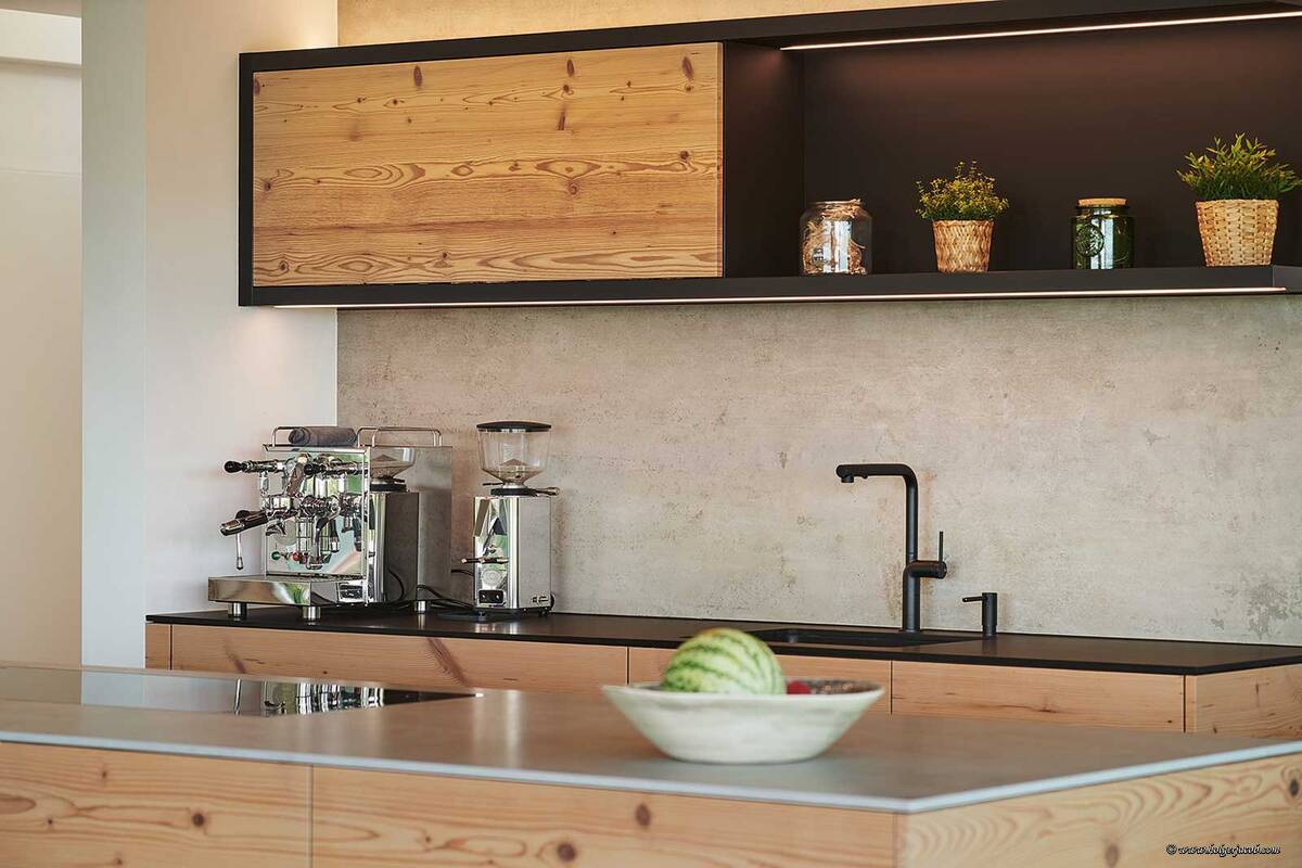 Umgebaut wurde zuerst die Küche, dann die gesamte Liegenschaft. So verhielt es sich auch mit dem Altholz, das als Erstes in Bezug auf die Küche zum Thema wurde und dann auch in weitere Räume kam. Das rustikale Holz wird mit der Beton–optik der Abdeckung und der Rückwand ausbalanciert. Brunner Küchen AG.