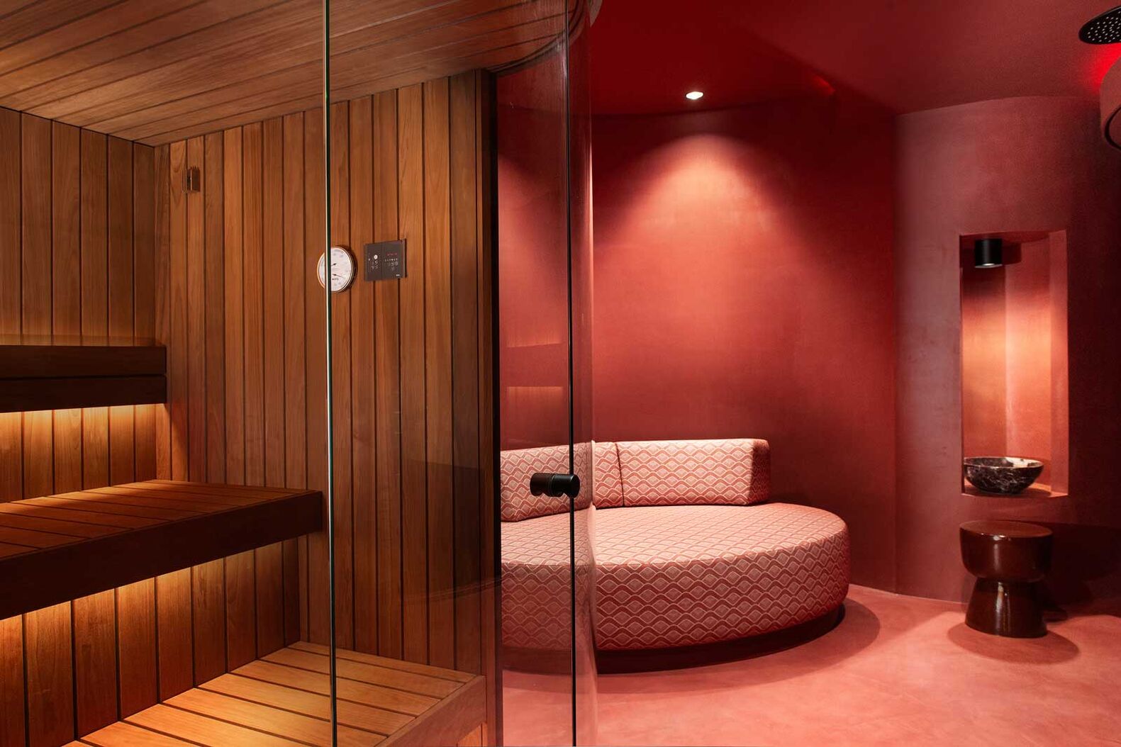 Wohlbefinden und Wärme liegen nah beieinander. In diesem privaten Wellnessbereich wurde dieser Umstand auch in der Farbpalette berücksichtigt. Das dunkle Holz der Innenverkleidung harmoniert mit dem Rot des Loungebereichs. Dort findet sich die runde Form des Raums in der Möblierung wieder. Moderne mit einem Hauch Vintage-Glamour. Küng Wellness AG, www.kueng.swiss