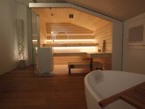 Auch eine Dachschräge erlaubt ein eigenes Wellness-Refugium. Die Sauna aus Espenholz lässt dank der Glasfront den Raum trotzdem grosszügig wirken. Ging Saunabau AG.